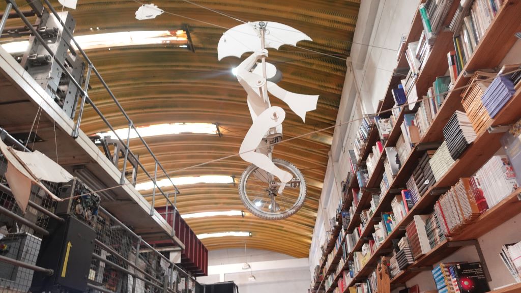 Rad-Kunst - Einradfahrer an der Decke zwischen Bücherregalen