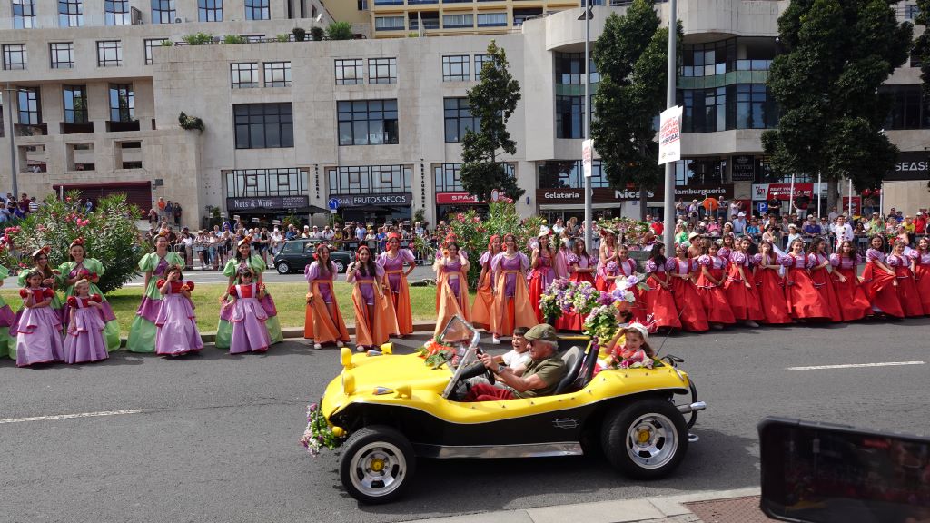 Tanzgruppen in farbenfrohen Kostümen begleiten die Oldtimer Auto Parade.