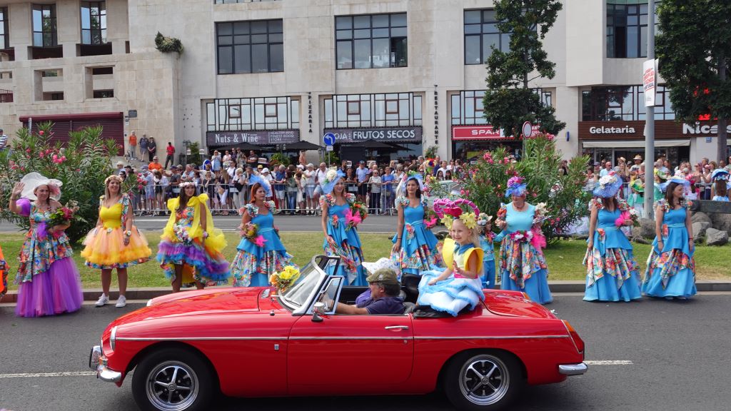 Tanzgruppen in farbenfrohen Kostümen begleiten die Oldtimer Auto Parade.