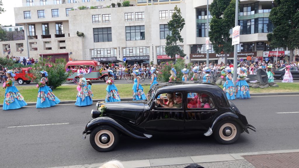 Tanzgruppen in farbenfrohen Kostümen begleiten die Oldtimer Auto Parade.