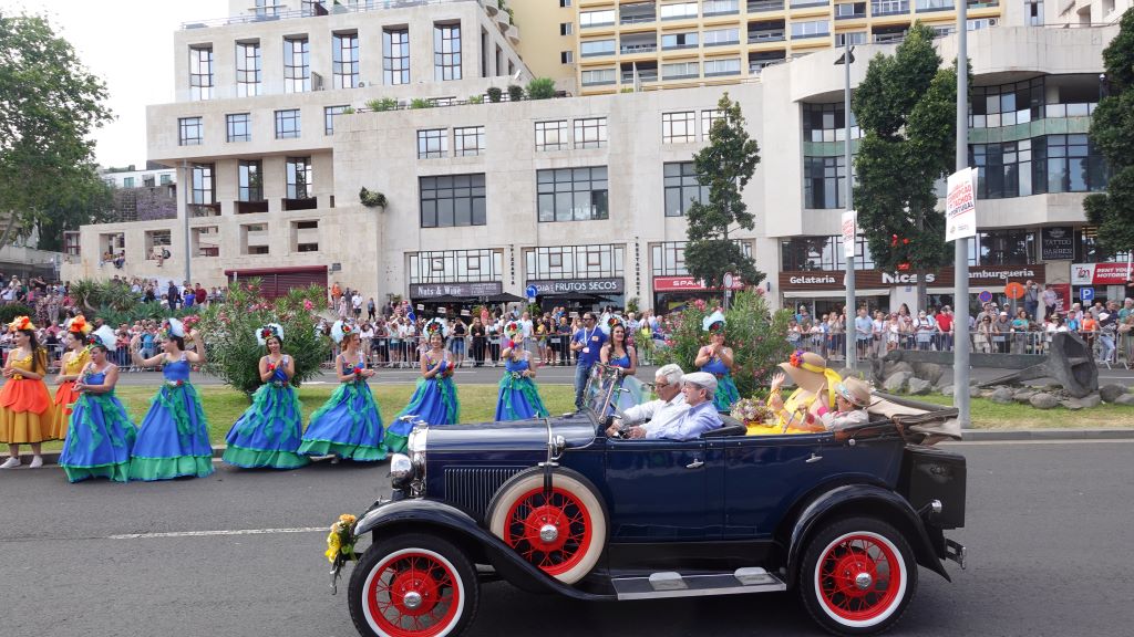 Tanzgruppen in farbenfrohen Kostümen begleiten die Oldtimer Auto Parade.