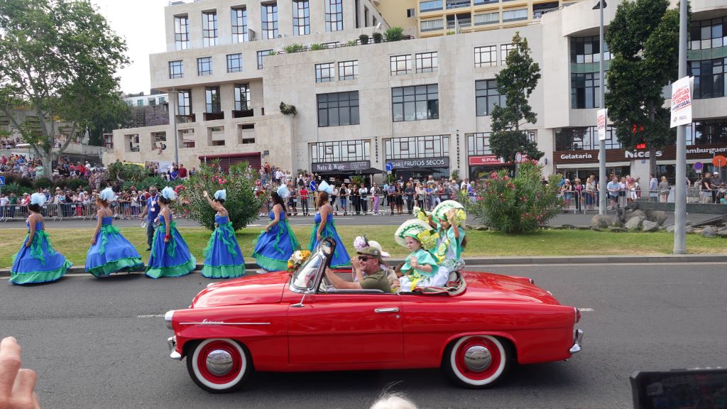 Tanzgruppen in farbenfrohen Kostümen begleiten die Oldtimer Auto Parade.