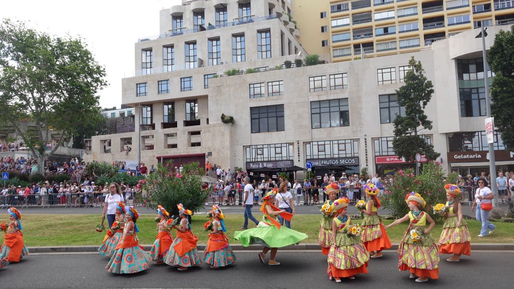 Tanzgruppen in farbenfrohen Kostümen begleiten die Oldtimer Auto Parade.