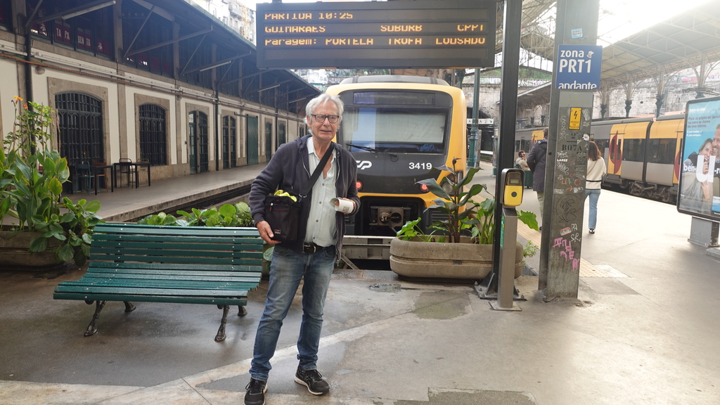 Klaus steht am Bahnhof und wartet auf den Zug nach Guimaraes