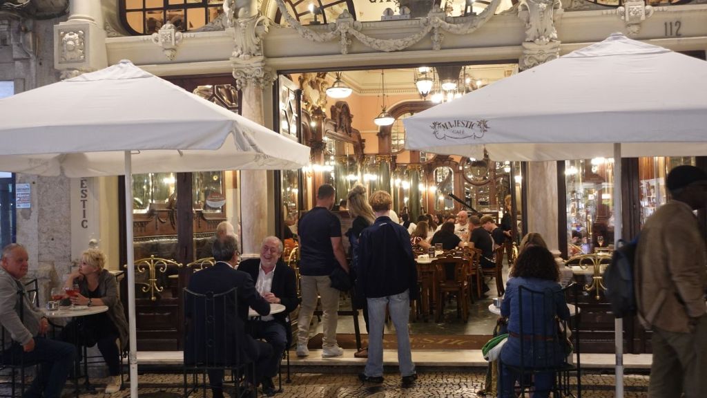 Blick von der Straße aus, mit Außentischen in den Gastraum des Belle-Epoque-Café Majestic in Porto