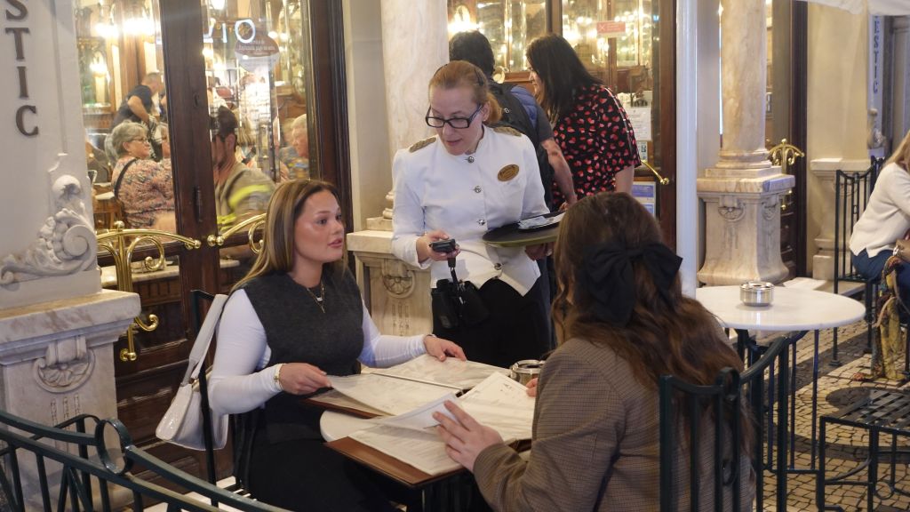 Elegant gekleidete Kellner und Kellnerinnen am Tisch zweier Gäste